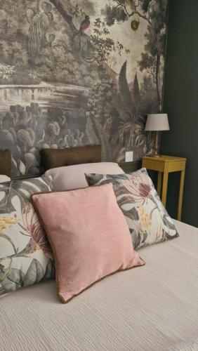a bed with a pink pillow on top of it at A la LampePigeon, un gîte avec jardin et du calme, 3 min de la Ferté-sous-Jouarre, 42 min de Paris TER, 35 min de Disney, 10 min de l'A4 in Reuil-en-Brie