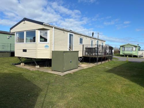 a tiny house is sitting in a yard at Jay 35 4 bed sleeps up to 8 dog friendly caravan Thornwickbay haven site on East coast in Flamborough