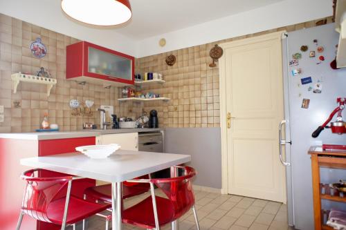 a kitchen with a white table and red stools at Melograni in Chomérac