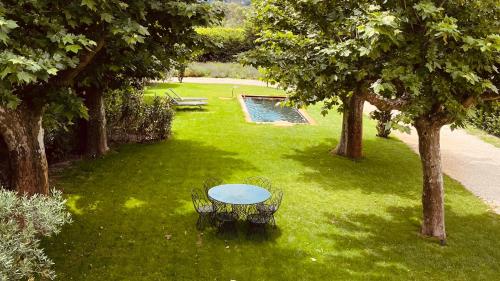 une table au milieu d'une pelouse avec des arbres dans l'établissement Mas Sylvestre Exceptional Stay in Provence, à Fontvieille