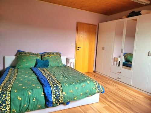 a bedroom with a bed with a green comforter at Gemütliche Ferienwohnung in Saarlouis-Fraulautern in Saarlouis