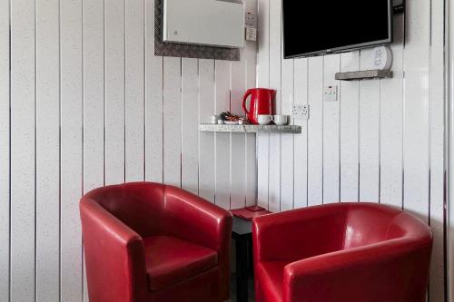 two red chairs in a room with a tv at Harlands Hotel in Blackpool