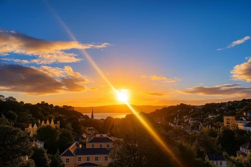 a sunset over a city with the sun in the sky at Nestee Serviced Apartments - Central Torquay - Pet Friendly - Harbour Views in Torquay
