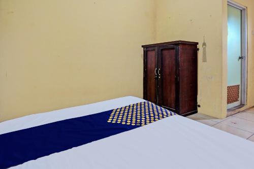 a bedroom with a bed and a wooden cabinet at Hotel O Lili Kost SyariahNearKetapang Royal City in Banyuwangi