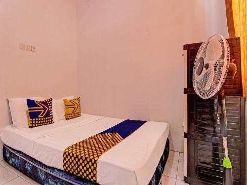 a bedroom with a bed and a fan at Hotel O Wisma Bani Pandi Syariah in Jepara
