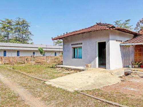 a small white house with a dirt road in front of it at Hotel O Wisma Bani Pandi Syariah in Jepara