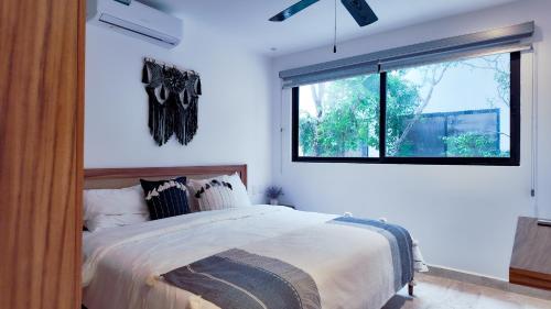 a bedroom with a large bed and a window at Town Center Zama Luxury Condo Hotel By Marea in Tulum