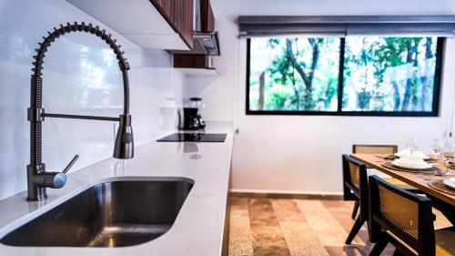a kitchen with a sink and a table and a window at Town Center Zama Luxury Condo Hotel By Marea in Tulum