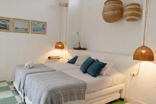 a white bedroom with a bed and two lamps at Casa Guerrero in Cartagena de Indias