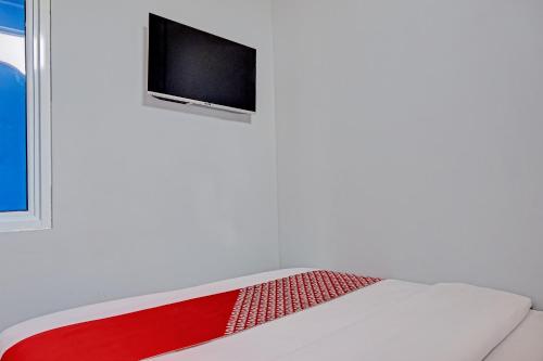 a room with a bed with a tv on the wall at Capital O 92765 J&b Smart Sentul in Bogor