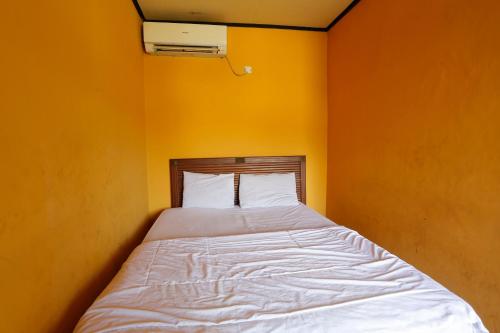 a bed in a room with an orange wall at Hotel O Rumah Kost Kita Tarakan in Tarakan