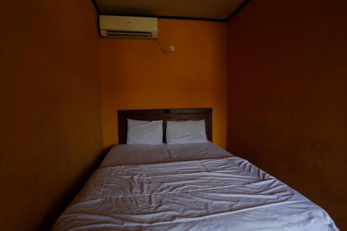 a bed in a bedroom with an orange wall at Hotel O Rumah Kost Kita Tarakan in Tarakan