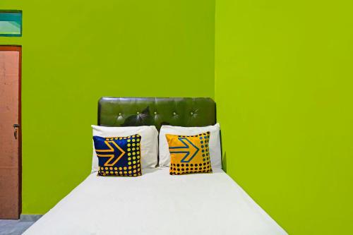 a green bedroom with a bed with two pillows at Hotel O Homestay Barokah in Gresik