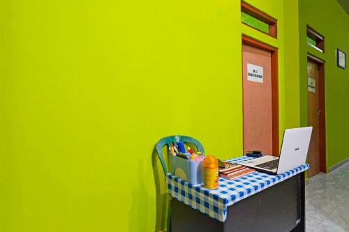 a desk with a laptop on a green wall at Hotel O Homestay Barokah in Gresik