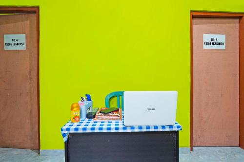 a table with a laptop on top of it in front of a green wall at Hotel O Homestay Barokah in Gresik