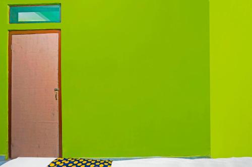 a green wall with a door in a room at Hotel O Homestay Barokah in Gresik