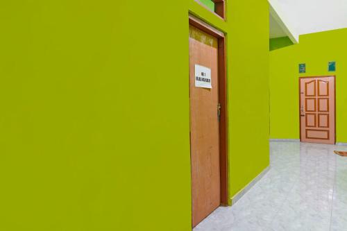 a green wall with a door in a room at Hotel O Homestay Barokah in Gresik