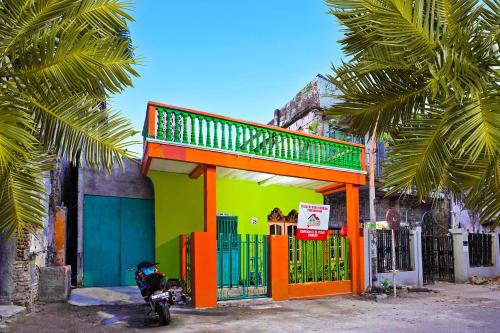a motorcycle parked in front of a green and orange building at Hotel O Homestay Barokah in Gresik