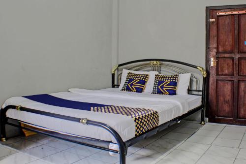 a bed with blue and white pillows in a room at Hotel O Badar Guest House Syariah in Bandar Lampung