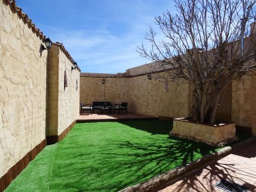 a yard with green grass next to a wall at Casa Rural El Breval in Alcazarén