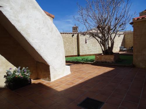 a brick courtyard with a tree and a building at Casa Rural El Breval in Alcazarén
