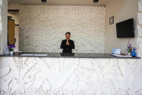 a man standing behind a counter in a room at Hotel O Tjokro 3 in Bogor