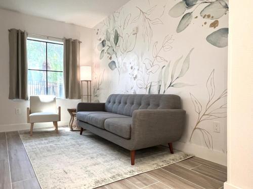 a living room with a couch and flowers on the wall at Condo close to Epic Universe - free parking in Orlando
