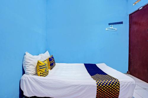 a bed in a room with a blue wall at Hotel O Lestari Syariah in Sidoarjo