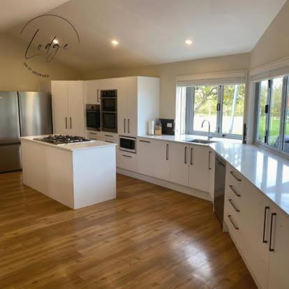a large kitchen with white appliances and wooden floors at Lodge On St Georges in Havelock North