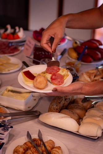 a person holding a plate of food on a table at Figueira do Rio do Boi Com Hidromassagem in Praia Grande