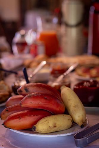 a plate of bananas and other food on a table at Figueira do Rio do Boi Com Hidromassagem in Praia Grande