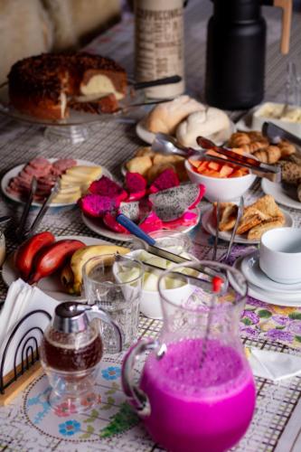a table topped with plates of food and a pink drink at Figueira do Rio do Boi Com Hidromassagem in Praia Grande