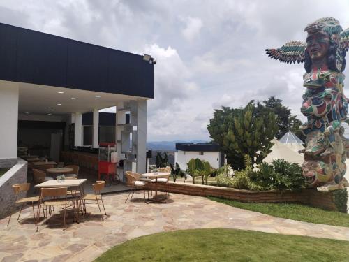 a large statue on the side of a building with a patio at Hotel PAUCHÉ Topiario Zapatoca in Zapatoca