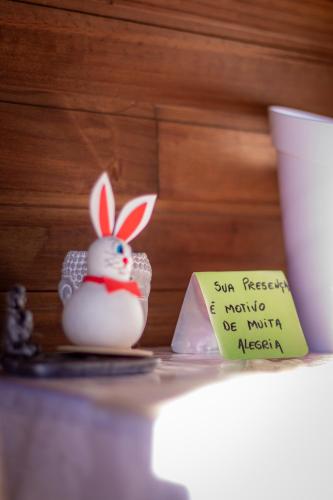 a toy bunny sitting on a table next to a sign at Figueira do Rio do Boi Com Hidromassagem in Praia Grande