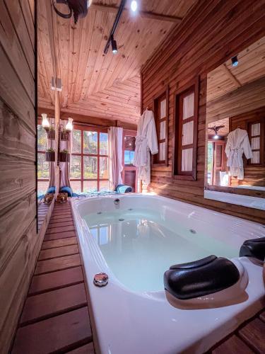 a large white bath tub in a wooden room at Figueira do Rio do Boi Com Hidromassagem in Praia Grande