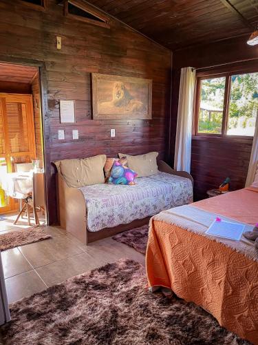 a bedroom with two beds and a couch with a stuffed animal at Figueira do Rio do Boi Com Hidromassagem in Praia Grande