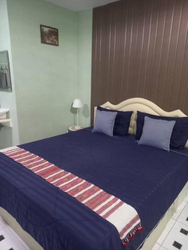 a large bed with a blue blanket and blue pillows at เอ็มยูโฮมรีสอร์ท in Ban Khlong Lam Hin