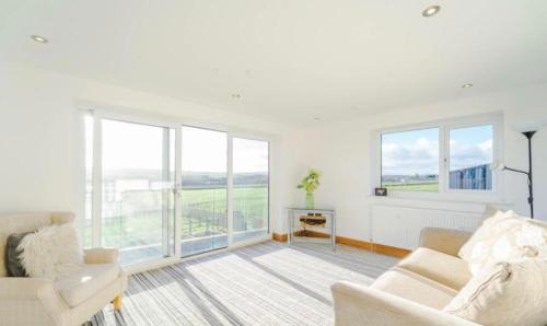 a white living room with a couch and windows at Oswaldtwistle Farmhouse in Oswaldtwistle