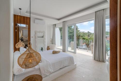 ein weißes Schlafzimmer mit einem Bett und einem großen Fenster in der Unterkunft Casa Auma Stunning 4 Bedroom Villa in Canggu in Tumbak Bayuh