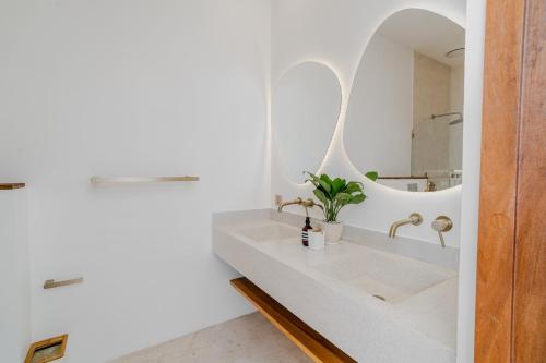 ein weißes Badezimmer mit Waschbecken und Spiegel in der Unterkunft Casa Auma Stunning 4 Bedroom Villa in Canggu in Tumbak Bayuh