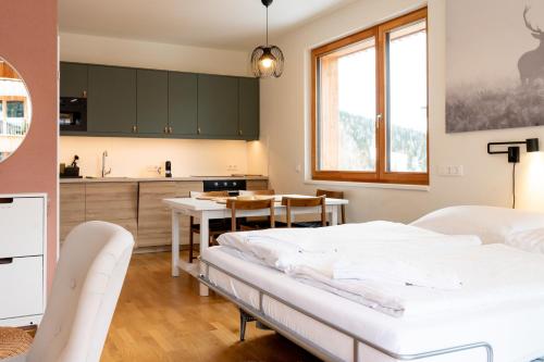 a bedroom with a bed and a table and a kitchen at AlmApp Nassfeld in Sonnenalpe Nassfeld