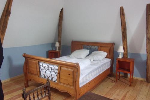 une chambre avec un lit en bois et deux tables de nuit dans l'établissement Le Four et l'Alambic Gîtes, à Pillac