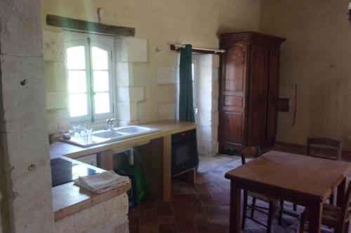 une cuisine avec un évier, une table et une fenêtre dans l'établissement Le Four et l'Alambic Gîtes, à Pillac