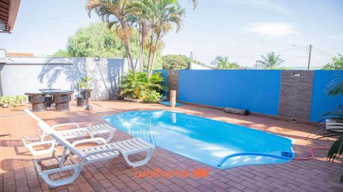 a swimming pool with two lawn chairs and a table at Casa com Piscina e Lazer Completo em Barra Bonita in Igarassú