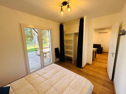 - une chambre avec un lit et une porte donnant sur une terrasse dans l'établissement Escale des grands lacs, à Gastes