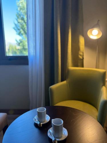 two coffee cups sitting on a table with a chair at Konke Calafate Hotel in El Calafate
