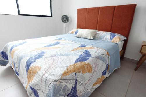 una camera da letto con un letto con una trapunta sopra di Apartamento frente a clínica Foscal a Floridablanca