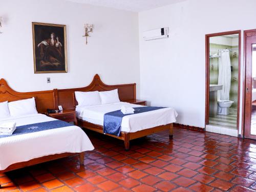 a hotel room with two beds and a bathroom at Hotel Frances in Guadalajara