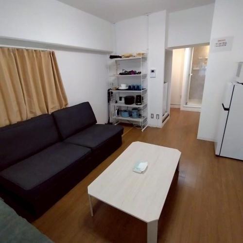 a living room with a black couch and a coffee table at JR Shin-Osaka 2mins, Direct to Kansai Airport 關西空港直達,Shinkansen to Tokyo, Tokyo & Nagoya, Universal Studio 16 mins, Umeda 6 mins, Kyoto 25 mins, Early Check-In in Osaka