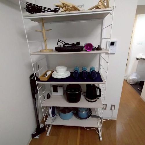 a shelf with dishes and other items in a room at JR Shin-Osaka 2mins, Direct to Kansai Airport 關西空港直達,Shinkansen to Tokyo, Tokyo & Nagoya, Universal Studio 16 mins, Umeda 6 mins, Kyoto 25 mins, Early Check-In in Osaka